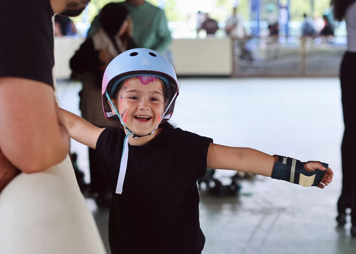 A laughing child in a helmet on the roller skating rink at Spelen bij Beelen